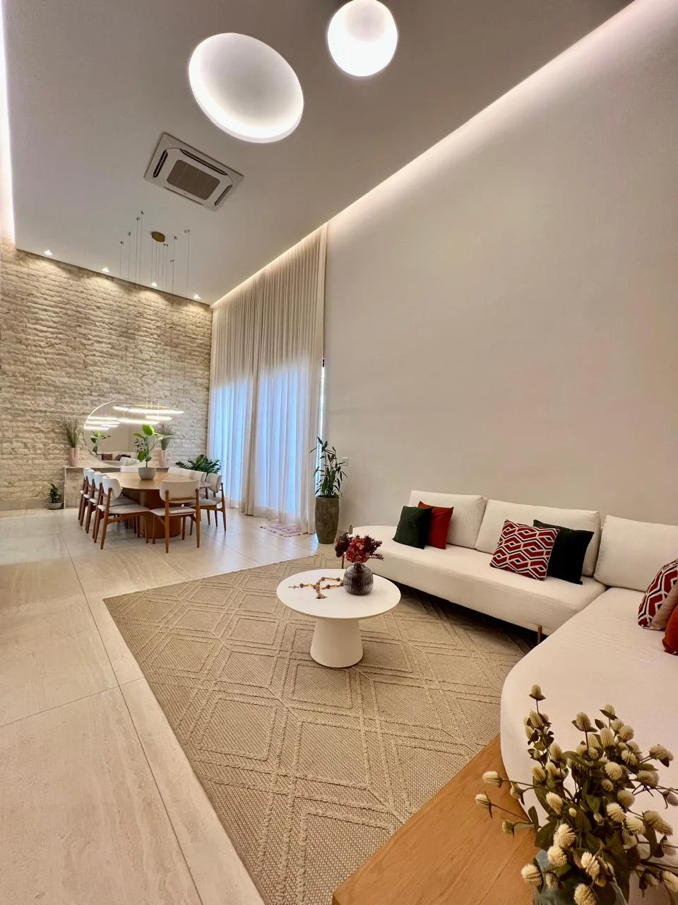 Living com pé direito duplo integrado e acabamento nobre na Casa Moderna Mobiliada do Condomínio Aldeia dos Sonhos